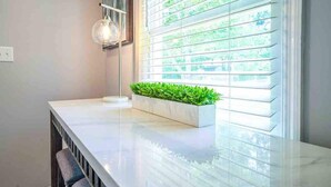 Una cocina moderna con encimera de mármol, un jardín vertical integrado y una lámpara colgante.