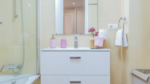 Ein modernes Badezimmer mit Badewanne, Dusche, Waschtisch und Spiegel sowie Toilette.