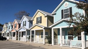 Une rangée de maisons colorées, toutes de plain-pied, avec des balustrades blanches, et un ciel d’un bleu limpide.