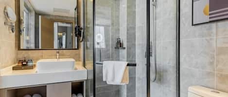 A modern bathroom with a glass-enclosed shower, a sink with a mirror, and a toilet.