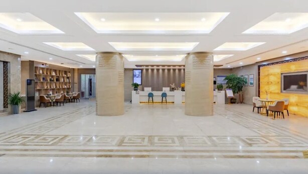 A spacious lobby with a reception desk, seating area, and a decorative wall.