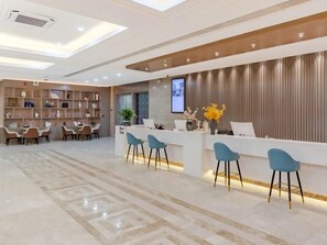 A reception area with a modern design, featuring a reception desk, seating area, and a wall-mounted television. - Greentree Eastern Chizhou Changjiang Middle Road Rt-mart Hotel (Chizhou)