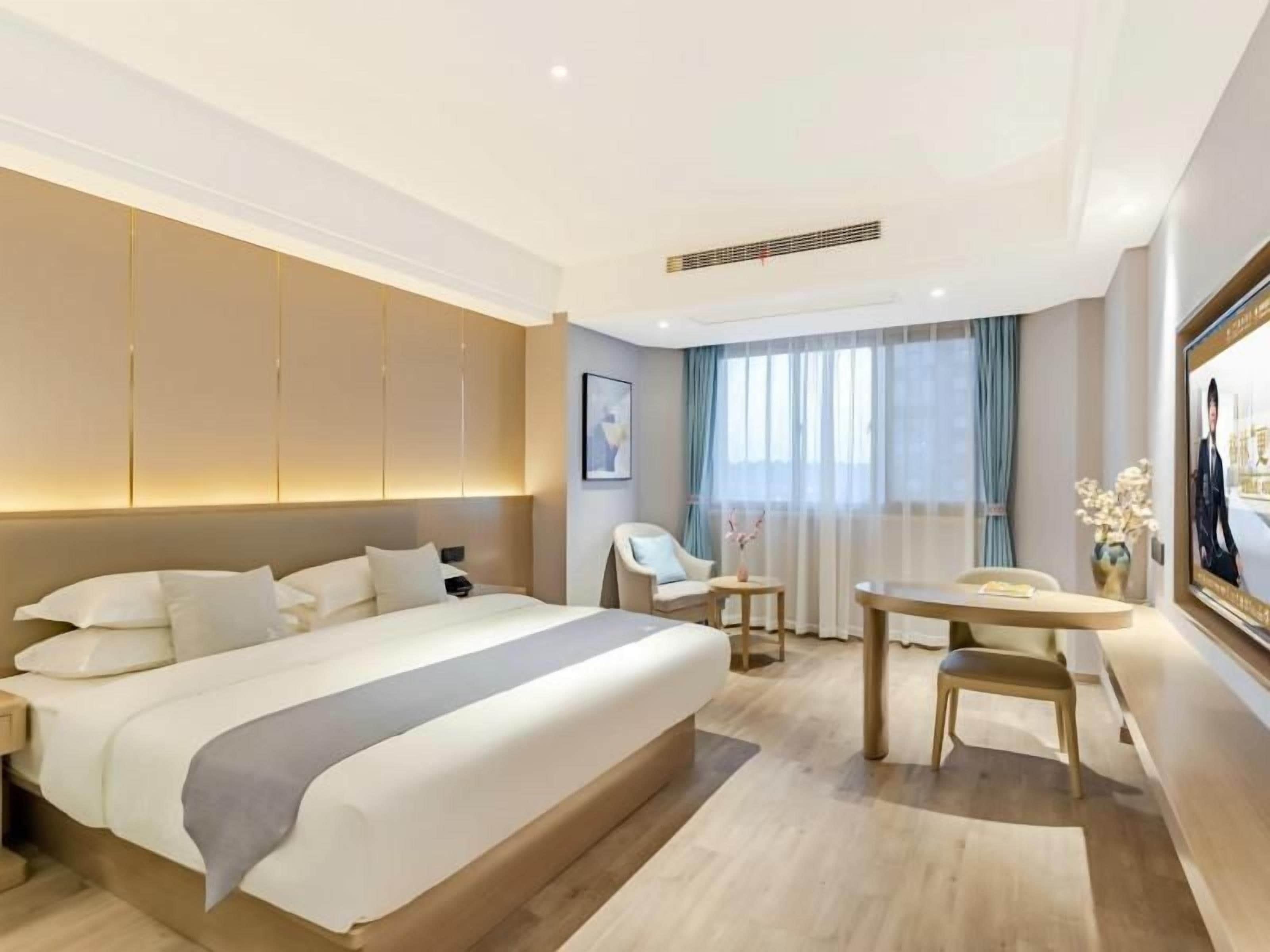 Ein modernes Hotelzimmer mit einem großen Bett, einem Schreibtisch und einem Fernseher.