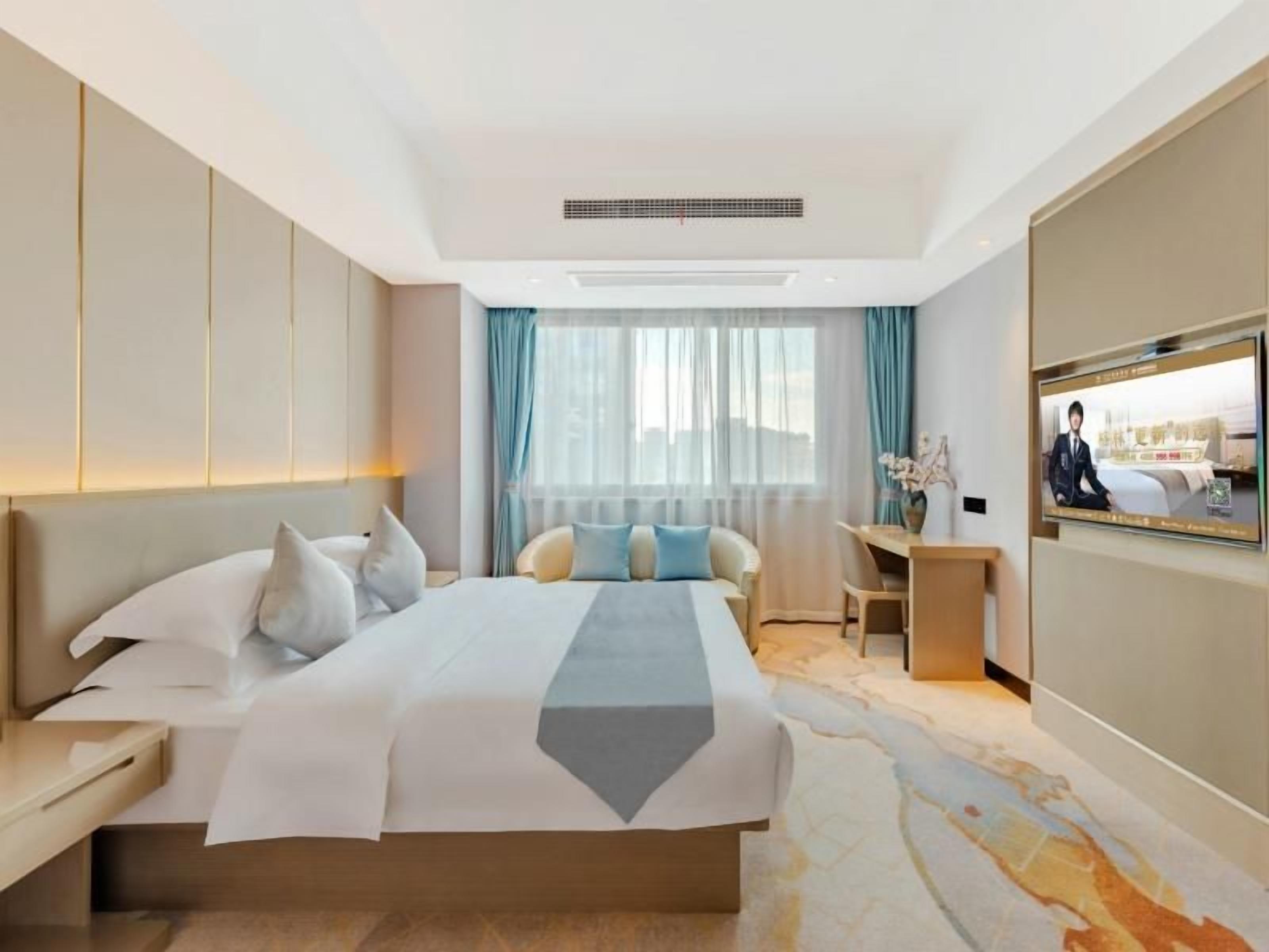 Een moderne hotelkamer met een groot bed, een bureau en een televisie.