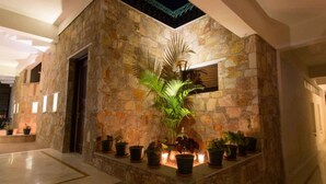 A stone-walled outdoor area with potted plants and candles, featuring a stone bench and a door. - Devraj Villa-A Luxury Homestay with Pool (Udaipur)