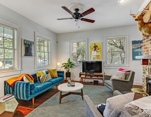 A living room with a blue sofa, a grey armchair, a TV, and a ceiling fan.