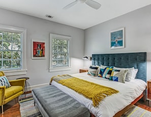 A modern bedroom with a large bed, a yellow armchair, and a bench.