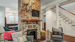 Una sala de estar con chimenea de ladrillo, una escalera y muebles modernos.