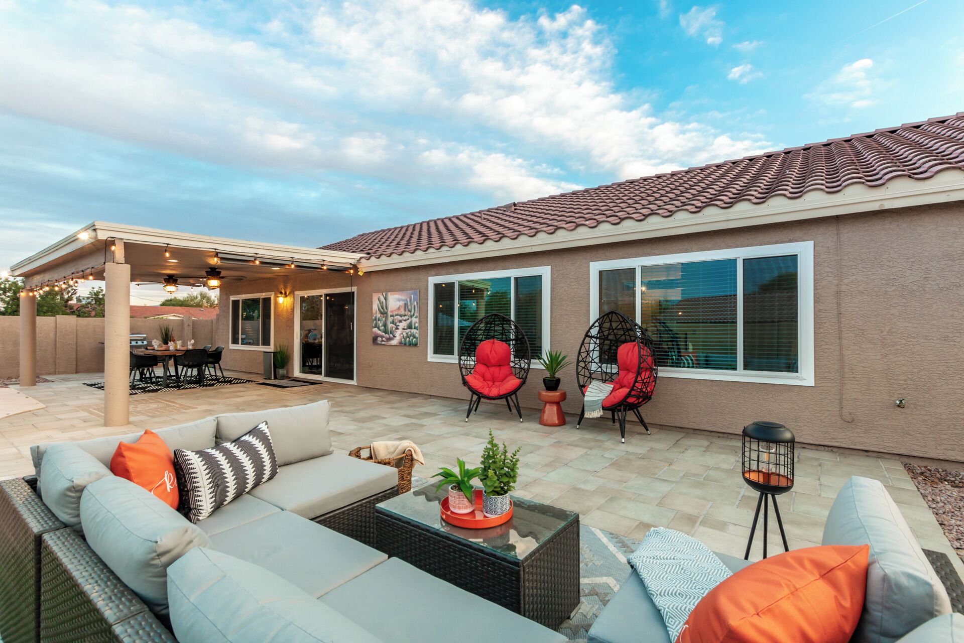 A covered patio area with outdoor furniture, including a sofa set and two red chairs.