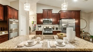 A modern kitchen with dark wood cabinets, stainless steel appliances, and a granite countertop. - 4BR w pool, game room, playground (Phoenix)