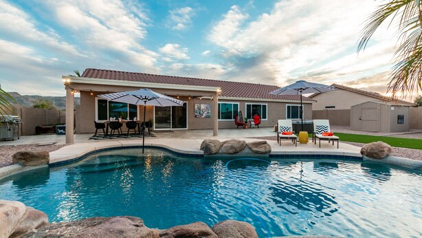 A residential pool area with a covered patio, outdoor seating, and a landscaped backyard. - 4BR w pool, game room, playground (Phoenix)