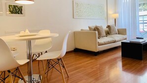 A modern living room with a dining table, white chairs, a beige sofa, and a black coffee table. - Palermo, Las Cañitas. In front of the Polo field. (Buenos Aires)