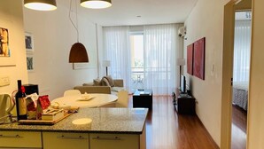 A modern kitchen with a granite countertop, a dining area with a round table, and a living room with a sofa and a TV. - Palermo, Las Cañitas. In front of the Polo field. (Buenos Aires)