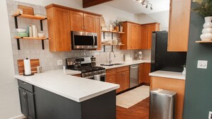 A modern kitchen with wooden cabinets, stainless steel appliances, and a central island. - The Toho-Tally Toho-Tel (Flagstaff)