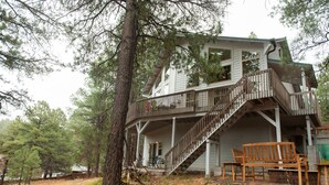 A two-story house with a wooden deck and stairs leading to a balcony. - The Toho-Tally Toho-Tel (Flagstaff)