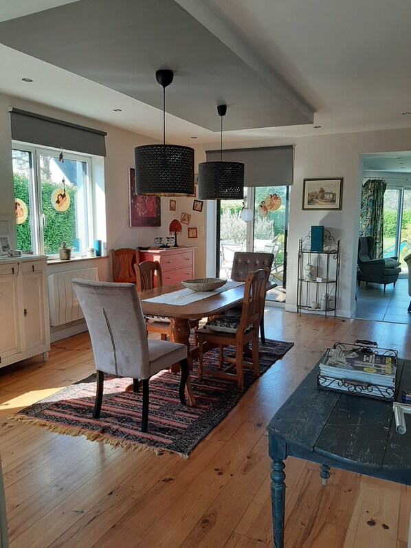 A spacious kitchen with wooden cabinets, a dining table with chairs, and pendant lights. - Seaside house (PRIMELIN)