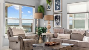 A living room with two beige sofas, a coffee table, and a large window with a view of the sky and mountains. - Lakeview Retreat with Private Firepit, Pinball, Backyard, Hot Tub, Free Tickets & Steps to Amenities (Branson)