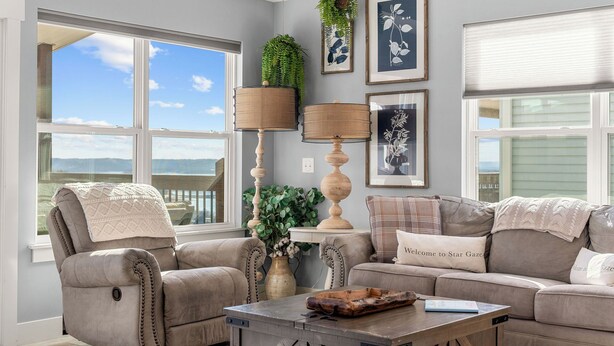 A living room with two beige sofas, a coffee table, and a large window with a view of the sky and mountains. - Lakeview Retreat with Private Firepit, Pinball, Backyard, Hot Tub, Free Tickets & Steps to Amenities (Branson)