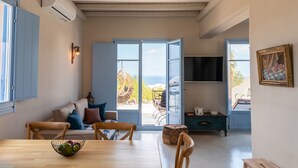 A cozy living room with a wooden table, a sofa, and a view of the outdoors. - Pink Freud Villas Santorini (Santorini)