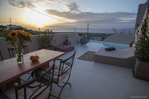 A rooftop terrace with a dining table, chairs, a small seating area, and a swimming pool. - Pink Freud Villas Santorini (Santorini)