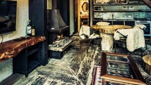 A rustic interior with a fireplace, wooden furniture, and a staircase. - Art Lodge Campos do Jordão (Campos do Jordão)