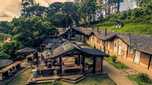 A rustic lodge with multiple wooden cabins, outdoor seating areas, and a central building with a sign. - Art Lodge Campos do Jordão (Campos do Jordão)