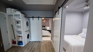 Habitació petita i funcional amb llit, armari i rentadora.