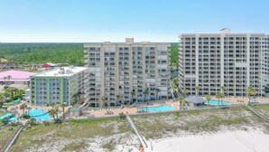 A multi-story hotel with a pool area, beach access, and a view of the surrounding landscape. - Shoalwater 106 | Beachfront Corner Condo | Indoor, Outdoor Pools | My Beach Getaways (Orange Beach)