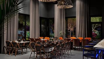 Een eetgedeelte met een lange tafel, meerdere stoelen en hanglampen.