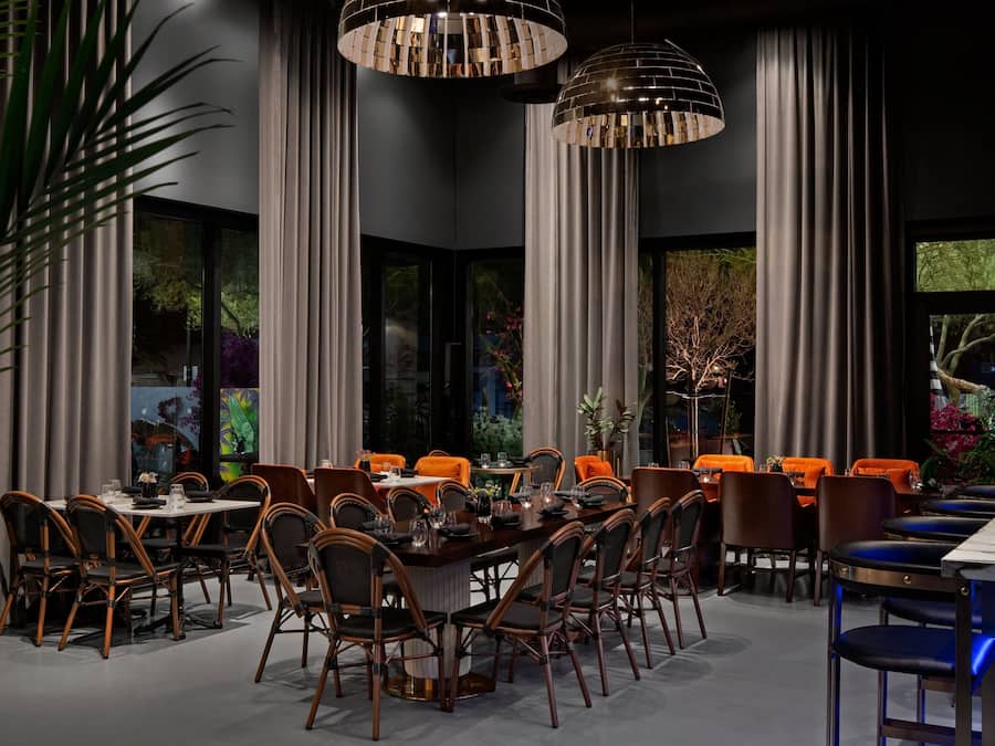 Een eetgedeelte met een lange tafel, meerdere stoelen en hanglampen.