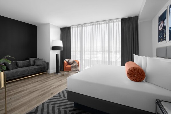 Una habitación de hotel moderna con una cama grande, un sofá, una silla y una lámpara de pie.