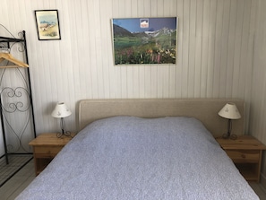 Ein Schlafzimmer mit einem Bett, zwei Nachttischen, zwei Wandlampen, einer hölzernen Kommode und zwei gerahmten Bildern.