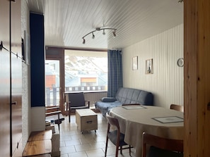A dining area with a table, chairs, and a view of mountains through a window.