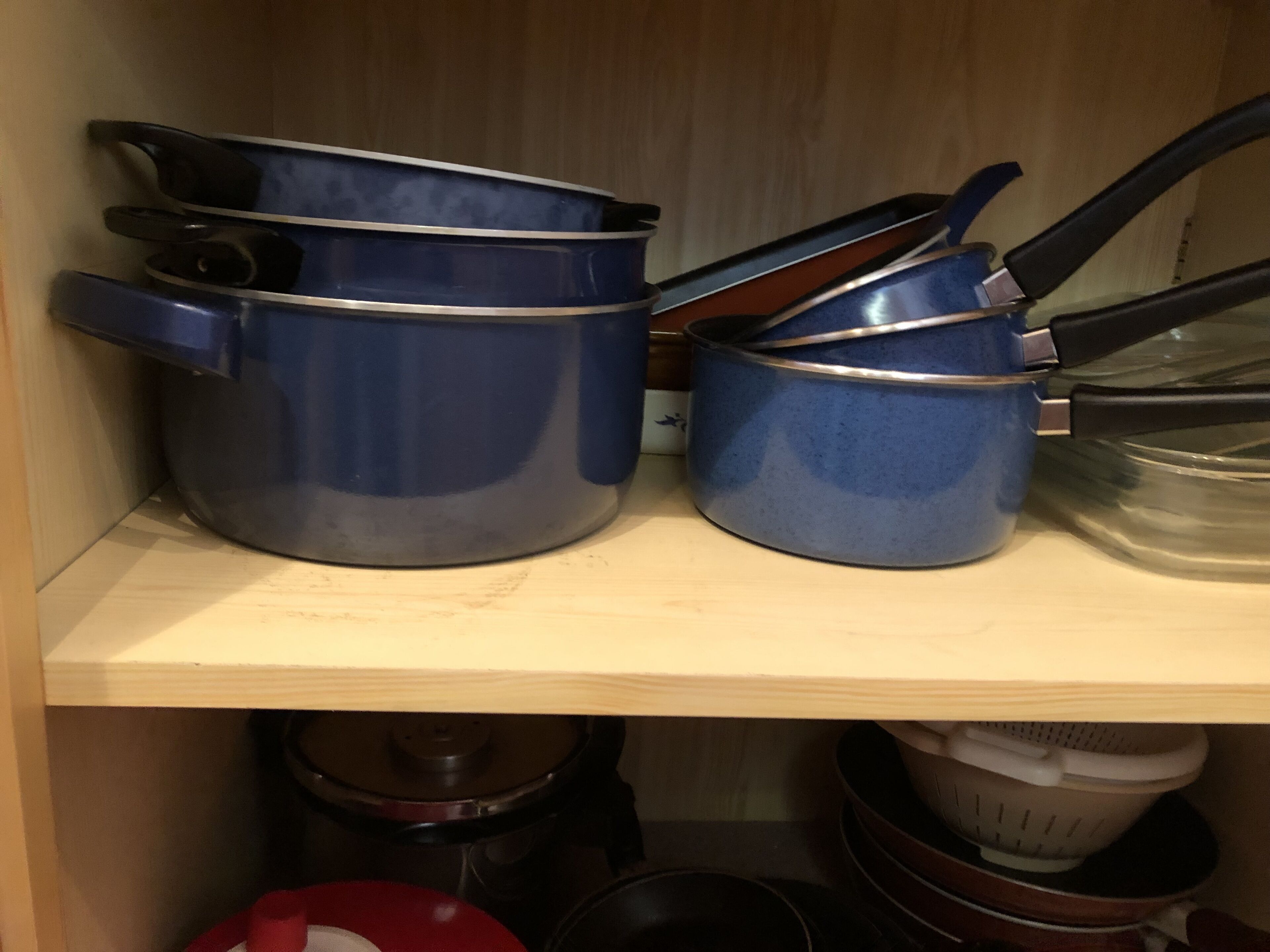 A kitchen shelf with various pots and pans.