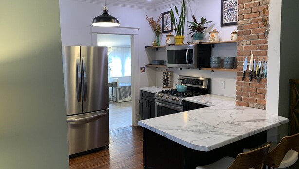 A modern kitchen with stainless steel appliances, a marble countertop, and a brick accent wall. - Sunny Stifft’s Station/Capital View: Off Street Parking AT&T Fiber (Little Rock)