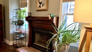 A living room with a fireplace, a bookshelf, and various potted plants. - Sunny Stifft’s Station/Capital View: Off Street Parking AT&T Fiber (Little Rock)