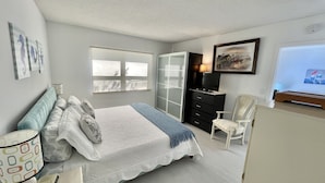 A bedroom with a bed, a dresser, a chair, and a window.