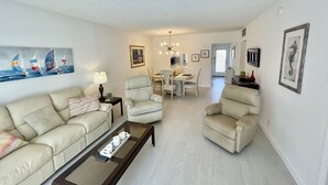 A living room with a sofa, armchairs, a coffee table, and a dining area with chairs and a table.