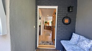 Ein Flur mit einer dunklen Ziegelwand, einem weißen Sofa und einem gemusterten Teppich.