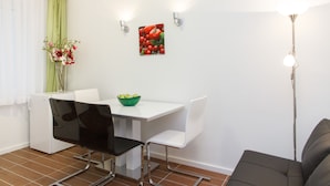 A dining area with a white table, black and white chairs, a green bowl, and a wall-mounted picture. - Apartment Jovanova (Belgrade)