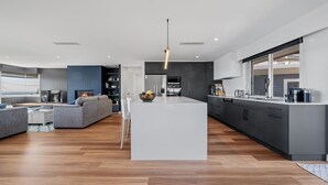 Una cocina moderna con una isla central, muebles oscuros y un ventanal grande.
