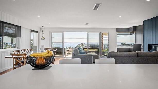 Una cocina moderna con una isla grande, comedor con sillas y vista al mar.