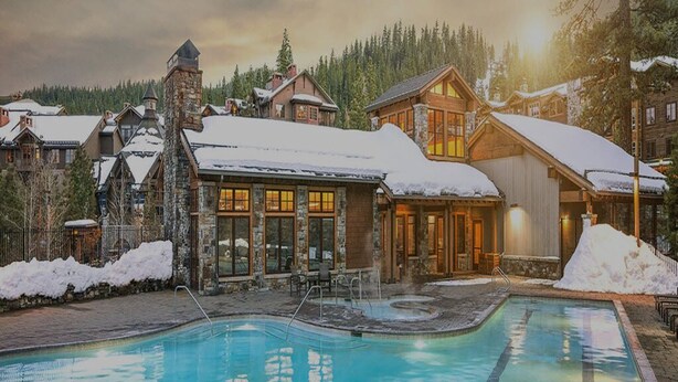 A resort with a swimming pool, stone buildings, and snow-covered surroundings. - Stay and Ski in Northstar Resort (Truckee)