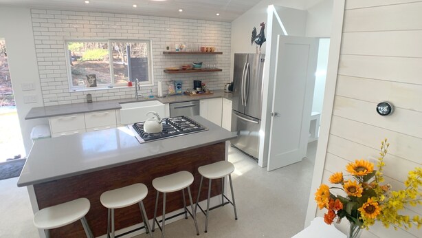 Una cucina moderna con isola centrale, elettrodomestici in acciaio inossidabile e sgabelli da bar.