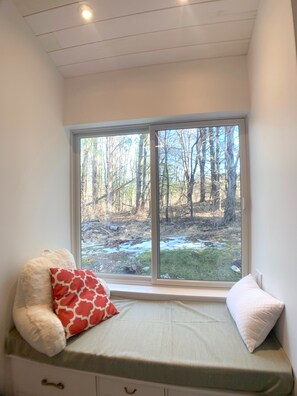 Un dormitorio con ventana que da a un bosque.
