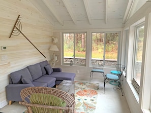Una habitación acogedora con un sofá modular, sillas de mimbre y un ventanal con vistas al exterior.