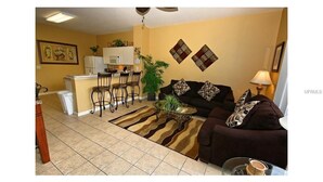 A living room with a sofa, coffee table, and a dining area with chairs and a table. - 3 Bedroom,3 Bath Townhouse in Gate Resort (Kissimmee)