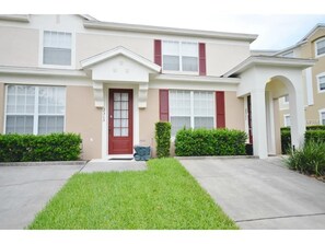 Stylish two-story home with a central entrance, red door, and well-manicured lawn.