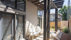 A covered patio with white Adirondack chairs, a wooden pergola, and a small garden area with plants and a wooden fence. - Walk to Broadway & Midtown • 5BR Townhouse Sleeps 12 • Private House Concert (Nashville)
