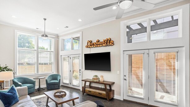 A spacious living room with a large TV, comfortable seating, and a ceiling fan. - Walk to Broadway & Midtown • 5BR Townhouse Sleeps 12 • Private House Concert (Nashville)